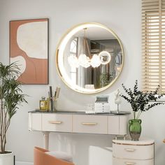 a white desk and chair with a round mirror on the wall above it next to a potted plant