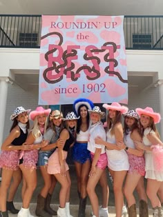 a group of women standing next to each other in front of a sign