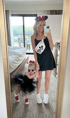 a woman taking a selfie with her daughter in front of a mirror wearing minnie mouse ears