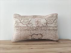 an embroidered pillow on top of a wooden table