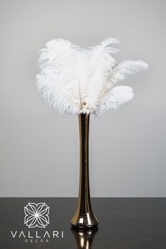 a vase with white feathers in it on a table