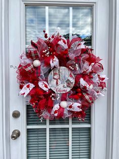 a red and white wreath on the front door of a house with welcome written on it