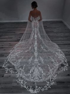 a woman in a wedding dress with a veil on her head is looking down at the floor