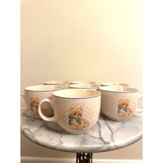 four coffee cups with teddy bears on them are sitting on a marble tray in front of a white wall