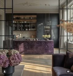 a living room filled with furniture next to a window covered in lots of purple flowers