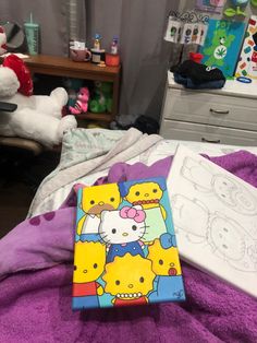 a hello kitty coloring book sitting on top of a bed next to a teddy bear