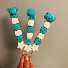 a person holding three blue and white candy lollipops with letters on them