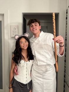 a man and woman are dressed up as mickey mouse and the girl is holding a stick