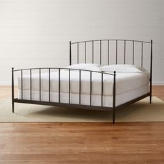 an iron bed frame with white sheets and pillows