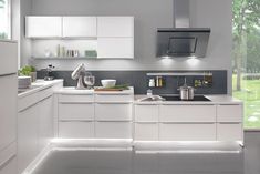 a modern kitchen with white cabinets and stainless steel appliances, including an oven hood over the sink