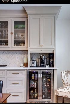 a kitchen with white cabinets and an open wine cooler in the corner next to a dining room table