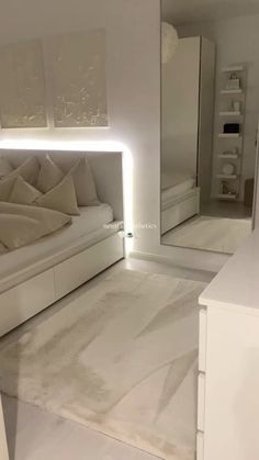 a white bed sitting in a bedroom next to a mirror on the side of a wall