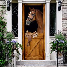 a wooden door with a horse head painted on it's side and flowers in the front