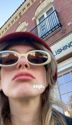 a woman wearing sunglasses and a hat with the word sup written on her face