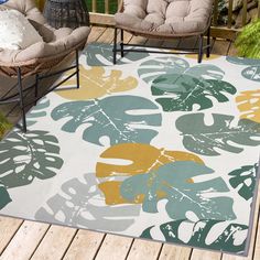 an outdoor area with chairs and rugs on the wooden deck, including two wicker chairs