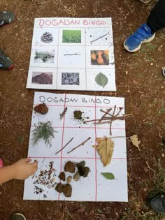 two children are looking at some plants and leaves on a sheet of paper that says dogaban bingo