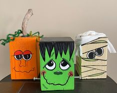 three painted pumpkins sitting on top of a table next to each other with faces drawn on them