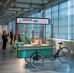 a green cart with some food on top of it in an airport terminal next to people