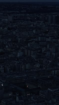 an aerial view of a city at night with the moon in the sky and buildings lit up