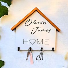 a house shaped key holder with two keys hanging from it's side and the words quija jamess home above it