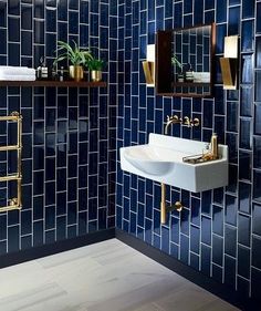 a blue tiled bathroom with gold fixtures and mirrors on the wall, along with a white sink