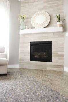 a living room with a fireplace, chair and vase on the mantel above it