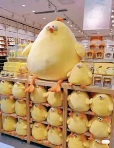 a large yellow stuffed animal sitting on top of a shelf in a store next to other stuffed animals