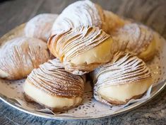 several pastries on a plate with powdered sugar and icing are sitting on the table