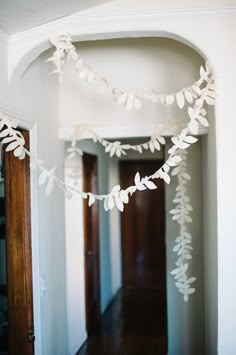 white paper leaves are hanging from the ceiling in this hallway, along with other decorations