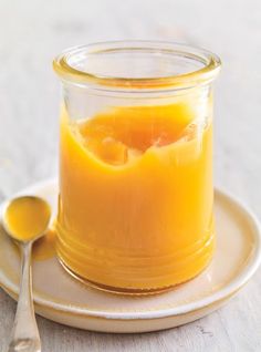 a glass jar filled with liquid sitting on top of a plate next to a spoon