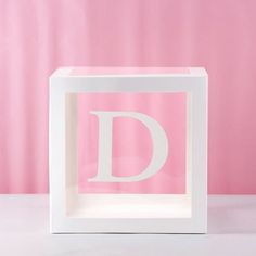 a white box with the letter d cut out in it's center, on a pink background