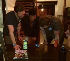 three men looking at a book on a table