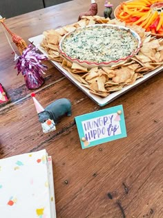 a wooden table topped with chips and dip