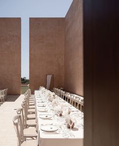 a long table with white plates and place settings in front of two large pink walls