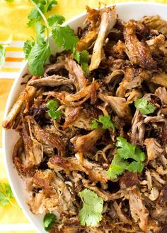 a white bowl filled with shredded meat and cilantro