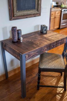 a wooden table sitting in the middle of a kitchen next to a chair and microwave