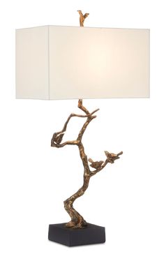 a table lamp with a bird on the branch design and a white shade over it