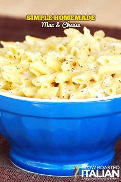 a blue bowl filled with macaroni and cheese sitting on top of a table