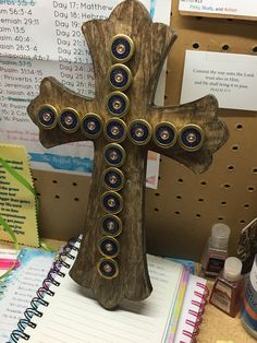 a wooden cross sitting on top of a desk next to a notepad and pen