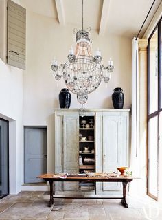 a chandelier hanging from the ceiling in a living room next to a table