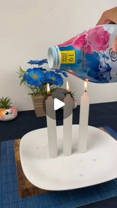 someone is pouring something into a cake with candles on it and flowers in the background