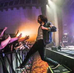 a man standing on top of a stage with his arms in the air while people are clapping