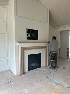 a man with a paint roller painting a fireplace in a room that is being remodeled