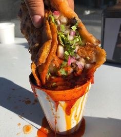 a person is holding up some food in a cup