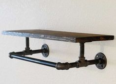 an industrial style shelf with pipes attached to it and two hooks on the wall above