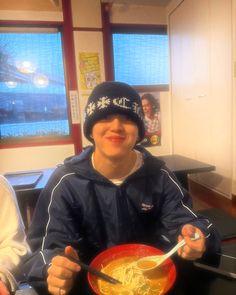 a person sitting at a table with a bowl of noodles