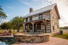 an old log house with a pool in the foreground