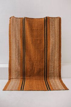 an orange and black striped rug on a white floor with a wall in the background