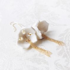 In the early spring, these small white snowdrops come up from the ground, excited to share the new season with you. They like facing down and showing you their charming curvy petals. Every porcelain snowdrop is handmade in unique shape. No two petals are exactly the same. Handmade porcelain snowdrops. Gold-filled long earring hooks. Gold-filled tassels. Gold-filled beads and wires. Gold-plated brass filigree. Swarovski beads. Handmade in Denmark. Gold- or silver-plated colour will fade over time Earring Tips, Snowdrop Flower, Long Earring, International Design, Handmade Earring, Swarovski Beads, Handmade Porcelain, Porcelain Jewelry, Beads And Wire