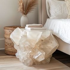 a white bed sitting next to a wooden table on top of a hard wood floor